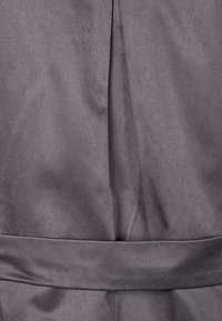 Gonna in tessuto grigio con una superficie liscia e strutturata, caratterizzata da una fascia in vita e dettagli sottili di pieghe.