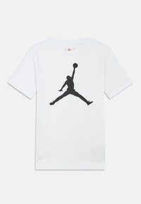 Biała bawełniana koszulka z dużym czarnym sylwetką koszykarza w skaczącej pozie, z logo "Jordan" nad sylwetką.