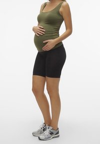 Mammatröja i olivgrön som matchas med svarta stretchiga cykelshorts. Modellen bär grå sportskor. Slät tyg, kroppsnära design.