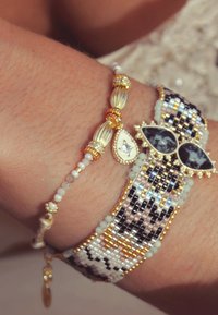Bracelets en perles dorées, noires et blanches. L'un présente de grands accents noir et blanc en forme de goutte d'eau, l'autre a des perles rondes.