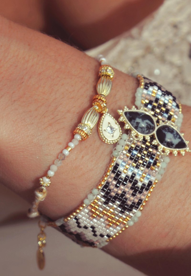 Bracelets en perles dorées, noires et blanches. L'un présente de grands accents noir et blanc en forme de goutte d'eau, l'autre a des perles rondes.