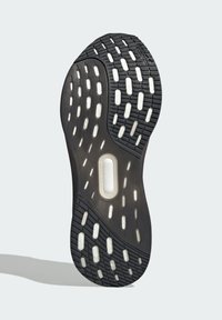 Černá podrážka sportovní obuvi s texturovaným gumovým povrchem s různými vzory a výřezy pro lepší trakci, včetně centrální tlumicí jednotky.