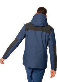 Granatowa wodoodporna kurtka z czarnymi akcentami, regulowanym kapturem i oddychającym materiałem. Posiada długie rękawy i luźny krój.