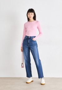 Langærmet ribbet pink top, højtaljede blå denim jeans, hvide sneakers med gule detaljer og en lille pink crossbody taske.