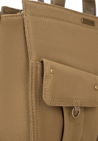 Borsa tote in tessuto beige con una finitura testurizzata, dotata di una tasca con patta, dettagli in metallo dorato e manici superiori.