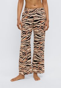 Pantalon léger et ample à motifs rayures de tigre dans des nuances de beige, marron et noir. Dispose d'une taille élastique.