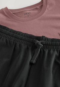 Mauve színű pamut férfi póló, kerek nyakkivágással, fekete, rugalmas derékpántos rövidnadrággal, amelyen zsinór is található.
