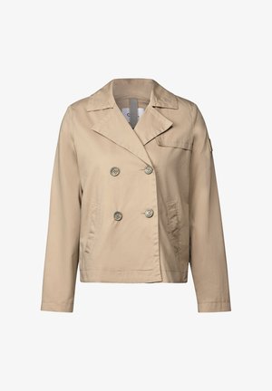 Beige takki, jossa on kaksinkertainen napitus, suuret napit, viisitaskut ja yksi rintatasku, valmistettu sileästä kankaasta.