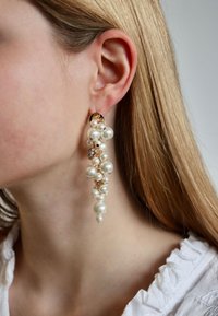 Gouden oorbellen met clusters van witte parels in verschillende maten. De parels zijn glad met een glanzende afwerking en hebben een watervallend ontwerp.