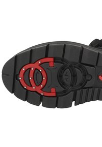 Suola di scarpa in gomma nera con profonde scanalature, accenti circolari rossi e borchie metallizzate incorporate per una migliore trazione.