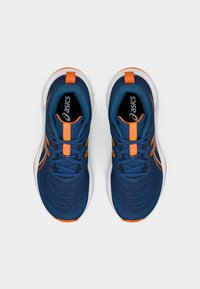 Μπλε αθλητικά παπούτσια με δικτυωτό πάνω μέρος, πορτοκαλί λεπτομέρειες και μαύρα κορδόνια. Διαθέτουν μαλακό πάτο και αεροδυναμικό σχέδιο.