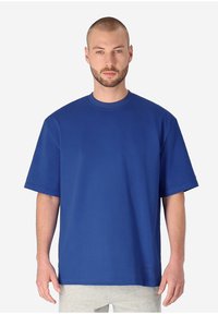 Blaues Baumwoll-T-Shirt mit kurzen Ärmeln, Rundhalsausschnitt und entspannter Passform. Glatte Textur mit dezentem Markenlogo nahe dem Saum.