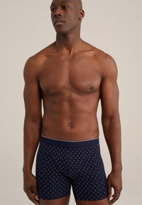 Mörkblå boxershorts med ett vitt geometriskt mönster, mjukt tyg, elastisk midjeband med kontrasterande kant, figursydd design.