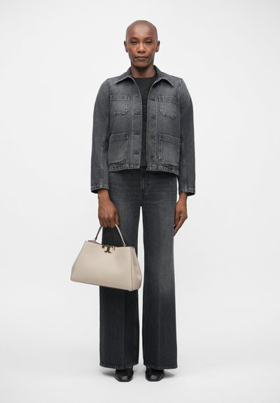 Grijze denimjack met twee voorzakken, gecombineerd met een bijpassende broek met wijde pijpen. Houdt een beige handtas met gouden accenten vast.