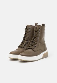 Bottes chevilles en cuir vert olive avec semelle en caoutchouc, bout rond et lacets à l'avant. Elles présentent une cheville rembourrée et des détails cannelés sur la semelle.