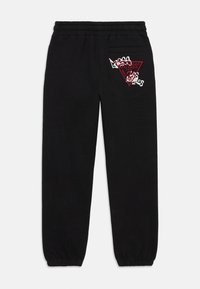 Schwarze Jogginghose mit elastischem Bund und Bündchen, mit einem roten Guess-Logo und weißem Graffiti-Text in der Nähe der hinteren Tasche.