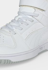 Λευκό sneaker υψηλού πάτου με κορδόνια και λουράκι Velcro, με επάνω μέρος από υφή δέρματος και λογότυπο Puma στο πλάι της σόλας.
