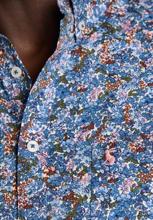 Hemd mit dichtem blauem, pinkem und grünem Blumenmuster, weißen Knöpfen und kleinem pinkfarbenem gesticktem Hasen auf der Tasche nahe dem Schlüsselbein.