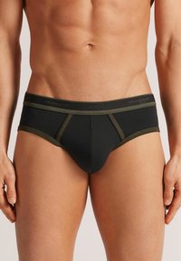 Svarta herrunderkläder med olivgrön trim, med en tight passform och mjukt tyg. Midjebandet har "intimissimi"-logotyp i matchande färger.