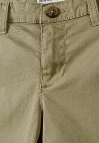 Pantaloni khaki in tessuto misto cotone, con chiusura anteriore a bottone, dettagli di cucitura sottili e una superficie liscia.