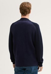 Granatowy sweter dziany z raglanowymi rękawami i ściągaczami. Miękka struktura, klasyczny kołnierz i bezszwowe plecy.