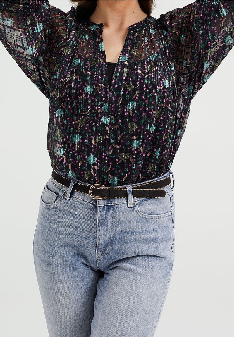Černá průsvitná blůza s barevným květinovým potiskem, skladovým vzorem a výstřihem ve tvaru V, spárovaná s světle modrými džíny a černým opaskem se stříbrnými detaily.