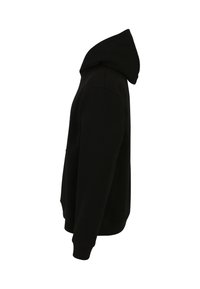 Musta huppari pehmeästä kankaasta, jossa on kengurupussi, ribbaatut hihansuut ja helma sekä kiristysnauha hupussa, esiteltynä sivulta.