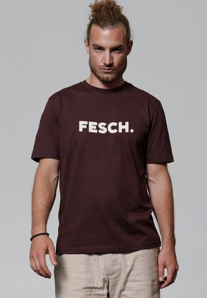 T-shirt en coton maroon avec un grand imprimé blanc "FESCH." à l'avant, col rond et manches courtes. Texture douce et coupe décontractée.