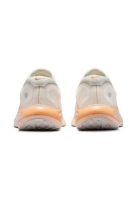 Paire de baskets Nike blanches et pêche, vues de dos, mettant en évidence les semelles et le design du talon avec des motifs circulaires.