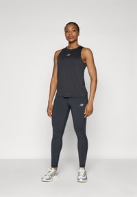 Čierny športový tielko a legíny vyrobené z elastického materiálu s priliehavým dizajnom; šedé bežecké topánky so striebornými akcentmi dopĺňajú tento outfit.