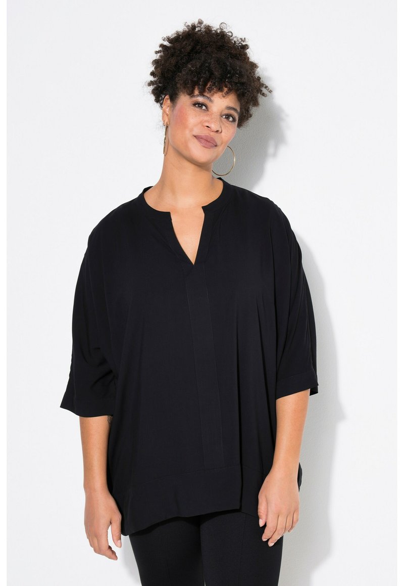 Maglietta nera ampia con scollo a placca e maniche corte. Tessuto liscio e design rilassato, adatta per un abbigliamento casual.