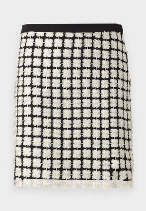 Fekete szoknya strukturált dizájnnal, fehér virágos hímzett mintákkal. Kiemelkedő részletei közé tartozik a rojtos díszítés az alján és a testhez simuló derékpánt.