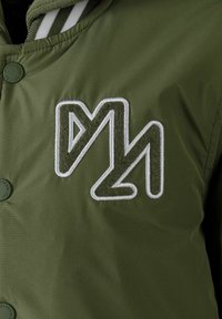 Zelená nadýchaná bunda s vyšitým logom v bielej a zelenej farbe. Hladká tkanina s matným povrchom, zahrňuje snap button zapínanie na ľavej strane.