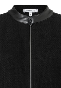 Schwarze Jacke mit Reißverschluss, strukturierter Stoff und Lederkragen. Verfügt über einen zentralen Reißverschluss und ein Etikett innen am Kragen. Größe 36.