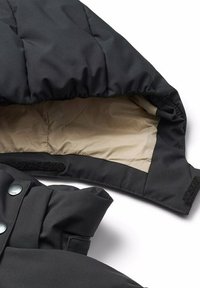 Giacca a vento nera con un morbido rivestimento beige, tessuto testurizzato e chiusura in Velcro. Presenta bottoni rotondi e un design del cappuccio strutturato.