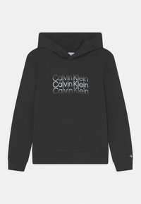 Sudadera negra de tela suave con un gran logo de Calvin Klein repetido en diferentes tonos de gris en la parte frontal.