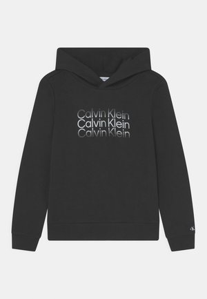 Schwarzer Hoodie aus weichem Stoff mit großem, wiederholtem Calvin Klein-Logo in verschiedenen Grautönen auf der Vorderseite.