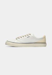 Baskets basses en toile pour homme en blanc cassé avec un talon beige, fermeture à lacets et logo "HUGO" sur le côté.