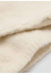 Cream-colored knitted fabric with soft texture, featuring three white buttons along the edge. Subtle patterning visible in the weave.