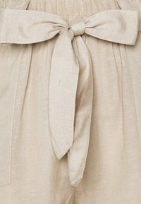 Béžová lněná tkanina s mašlí v pase, s texturovaným povrchem a nařaseným elastickým pasem.