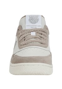 Baskets blanches et beiges en suède et cuir, avec une semelle texturée, de larges lacets et un logo en patch avec des détails métalliques sur la languette.