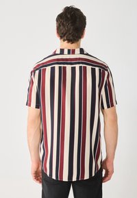 Camisa de manga corta con rayas verticales en colores azul marino, burdeos y crema. Tejido suave con corte relajado y cuello puntiagudo.