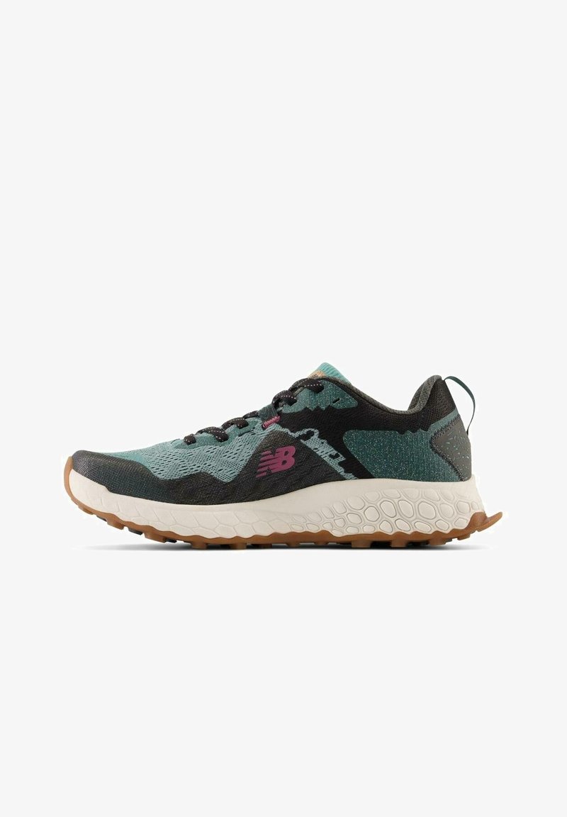 Hardloopschoen met een ademend mesh bovenwerk in teal en zwart, voorzien van een roze logo, een gewatteerde witte zool en een bruine rubberen buitenzool.