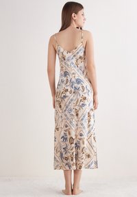Vestito color crema con motivo floreale, caratterizzato da spalline sottili, lunghezza fino al polpaccio e una texture liscia e setosa con dettagli a cucitura diagonale.