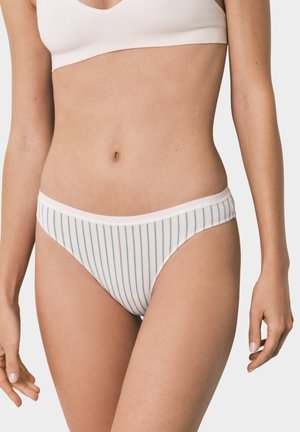 Kvinde iført hvid bikini-style undertøj med tynde lodrette grønne striber og en matchende beige bh, vist fra mellemtorso til øvre lår.