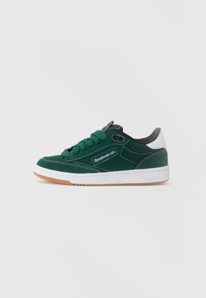 Sneaker verde din suede cu accente negre, branding alb și talpă din cauciuc de tip gumă. Dispune de limbă căptușită și design cu șireturi.
