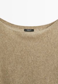 Pull en tricot beige avec un large décolleté arrondi. La texture est douce et légèrement duveteuse. L'étiquette présente la marque "Massimo Dutti".