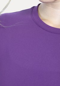 Fioletowy sportowy top z okrągłym dekoltem, gładką fakturą i krótkimi rękawami, wykonany z elastycznego materiału odpowiedniego do aktywności fizycznej.