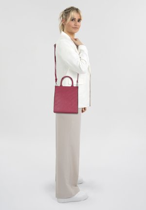 Sac à main rectangulaire rose avec un motif texturé, une poignée supérieure et une bandoulière réglable, présenté sur un fond neutre.