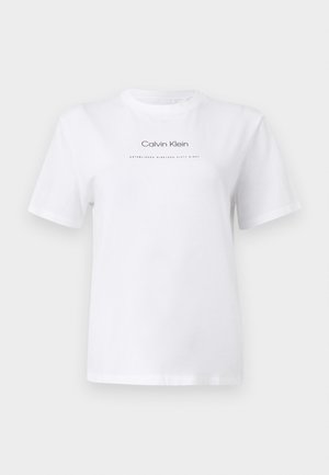 Bijela majica kratkih rukava s okruglim izrezom i logotipom "Calvin Klein" te tekstom "Established Nineteen Sixty Eight" u sredini prsa.